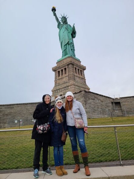 posing in front of the statue of liberty
