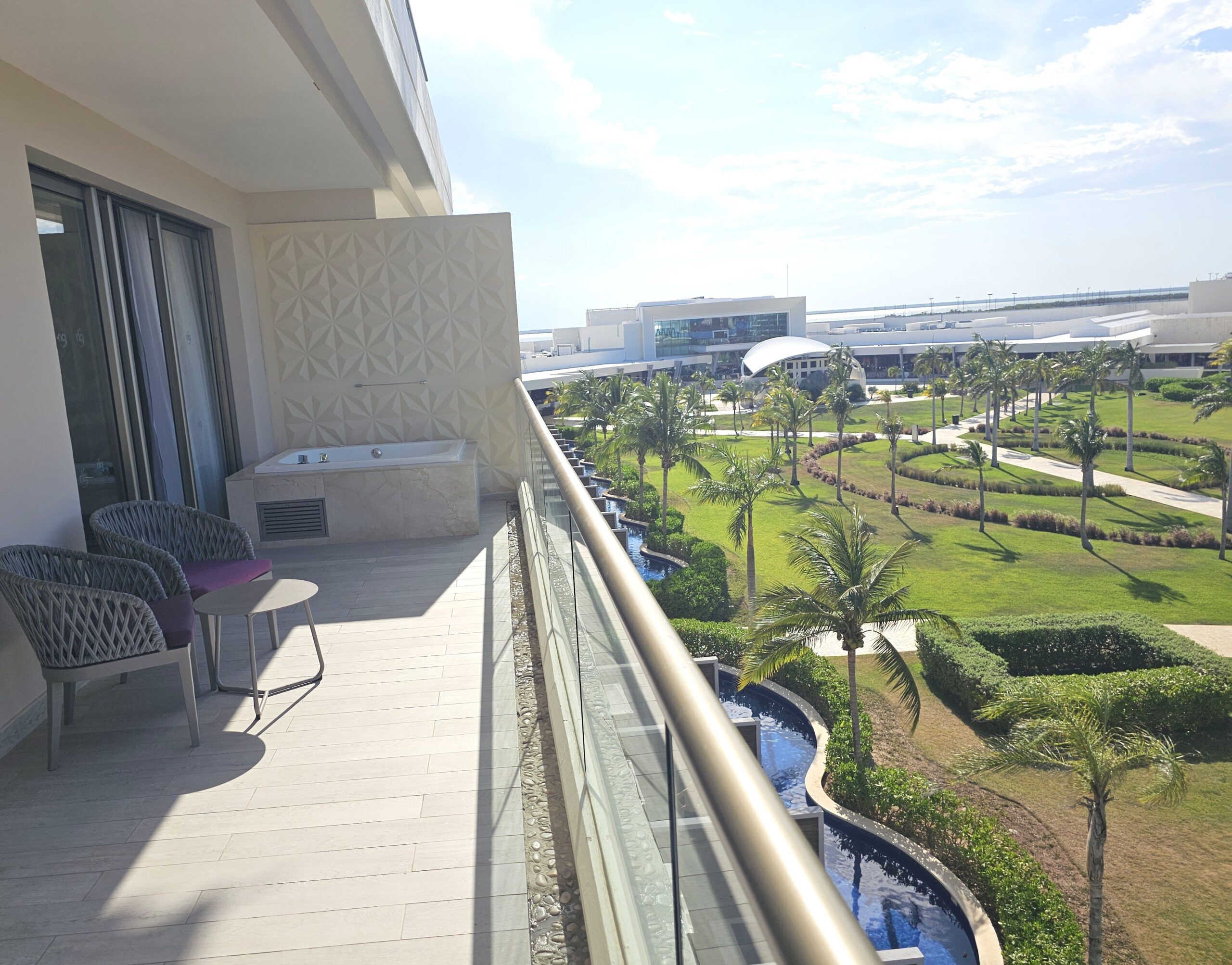 The view from a balcony at planet hollywood cancun overlooking swim out pools, greenery, and the main stage entertainment area