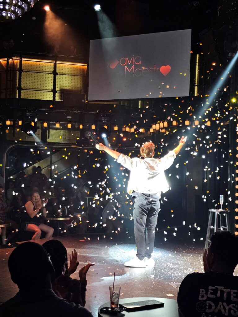 a magician is surrounded by confetti after doing a trick on a scarlet lady virgin voyages cruise 